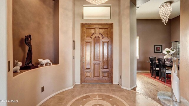 tiled entryway with a chandelier and a towering ceiling