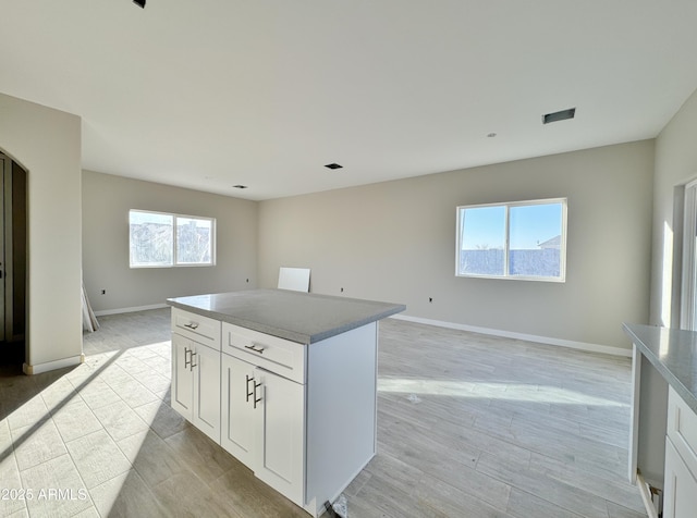 kitchen with a healthy amount of sunlight, a kitchen island, and white cabinets