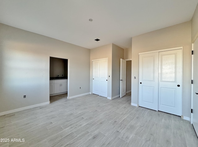 unfurnished bedroom featuring ensuite bath and light hardwood / wood-style flooring