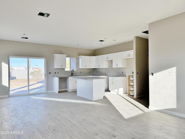 kitchen featuring white cabinetry, sink, a center island, and light wood-type flooring