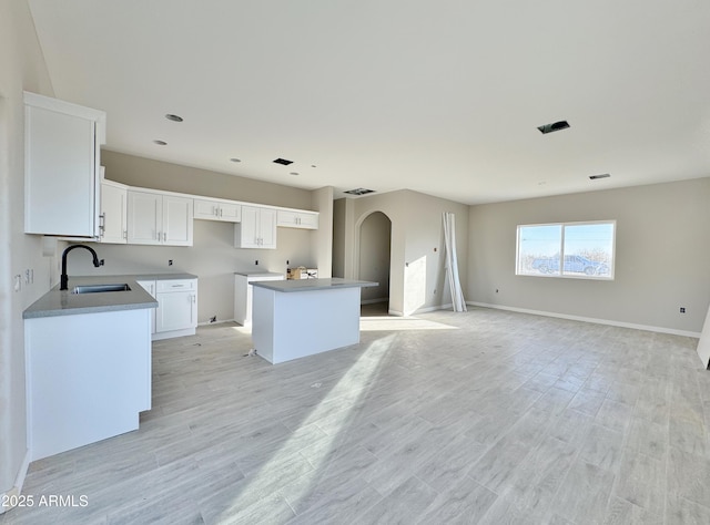 kitchen featuring sink, light hardwood / wood-style floors, white cabinets, and a kitchen island