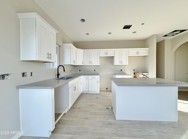 kitchen with white cabinetry, sink, and a kitchen island