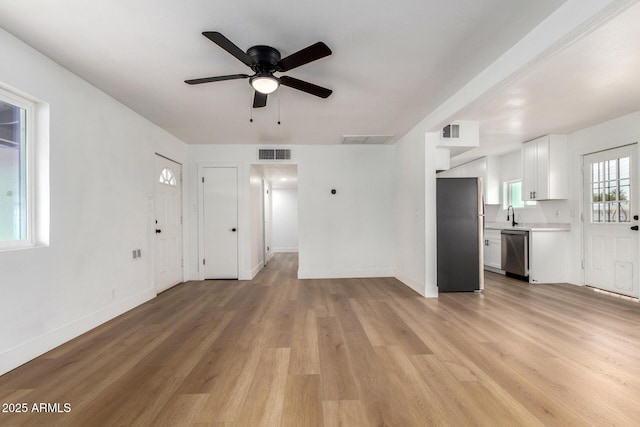 unfurnished living room featuring baseboards, visible vents, and light wood-style floors