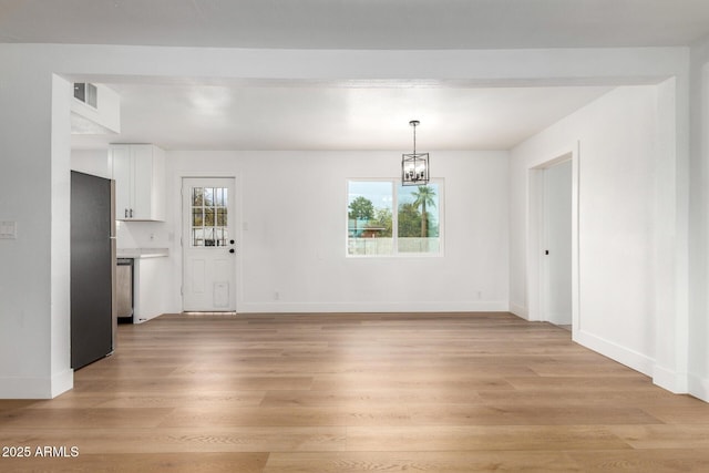 unfurnished dining area with light wood-style floors, visible vents, baseboards, and an inviting chandelier