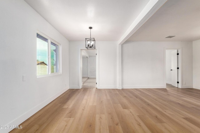 unfurnished dining area featuring visible vents, a notable chandelier, light wood-style flooring, and baseboards