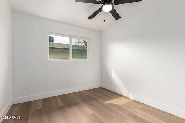 empty room featuring ceiling fan, light wood-style flooring, and baseboards