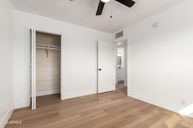 unfurnished bedroom with a closet, visible vents, light wood-style flooring, ceiling fan, and baseboards