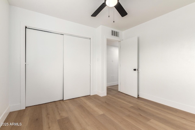 unfurnished bedroom with baseboards, visible vents, light wood-style flooring, ceiling fan, and a closet