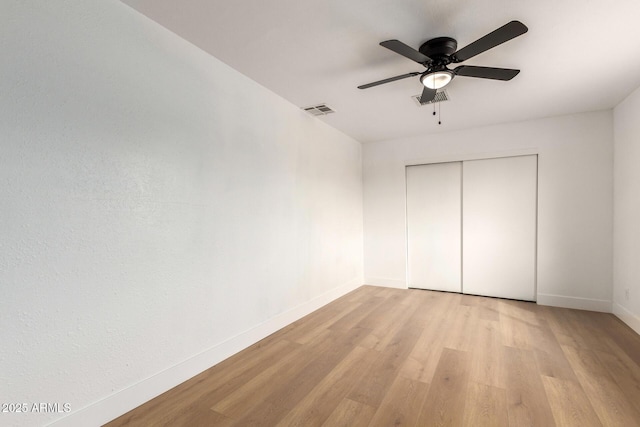 unfurnished bedroom featuring a ceiling fan, visible vents, baseboards, a closet, and light wood finished floors