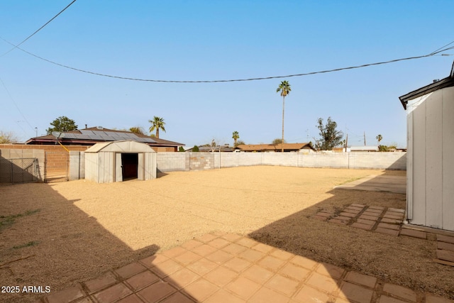 view of yard featuring a fenced backyard, a storage unit, and an outbuilding