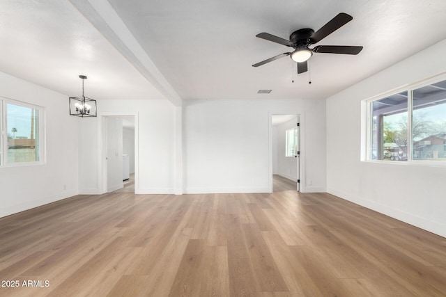 unfurnished room with baseboards, ceiling fan with notable chandelier, visible vents, and light wood-style floors