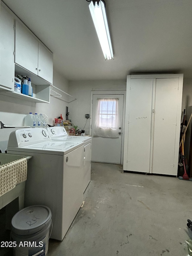 clothes washing area with cabinets and washer and clothes dryer