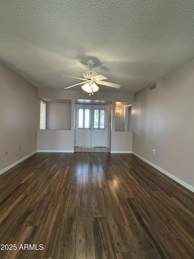 empty room featuring ceiling fan, a textured ceiling, and dark hardwood / wood-style flooring