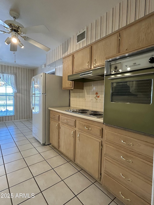 kitchen featuring light tile patterned flooring, stovetop, oven, white fridge, and ceiling fan