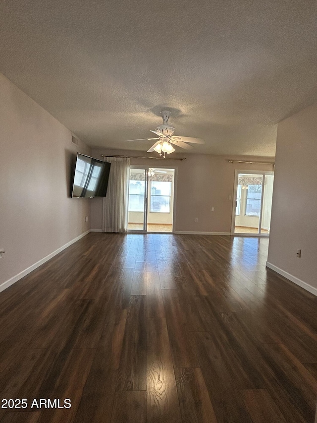 unfurnished room with ceiling fan, a textured ceiling, dark wood-type flooring, and a healthy amount of sunlight