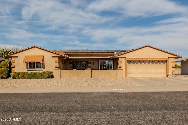 ranch-style house featuring solar panels, an attached garage, driveway, and stucco siding