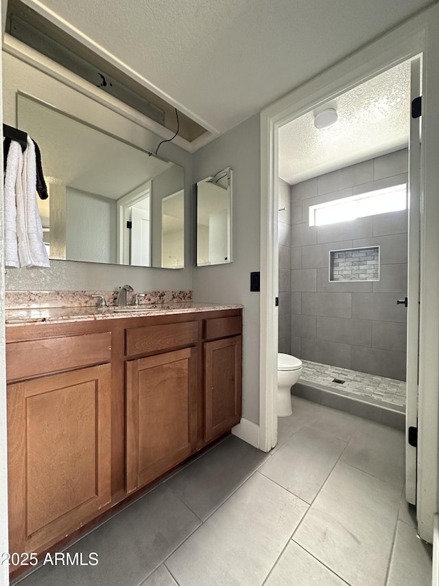 5924 W Tierra Buena Ln, Glendale, AZ 85306 - full bathroom featuring a textured ceiling, a tile shower, toilet, tile patterned flooring, and vanity