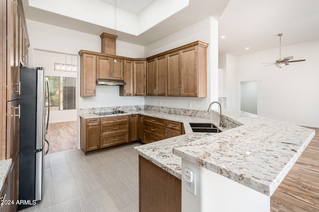 kitchen with light hardwood / wood-style floors, sink, kitchen peninsula, light stone countertops, and stainless steel fridge