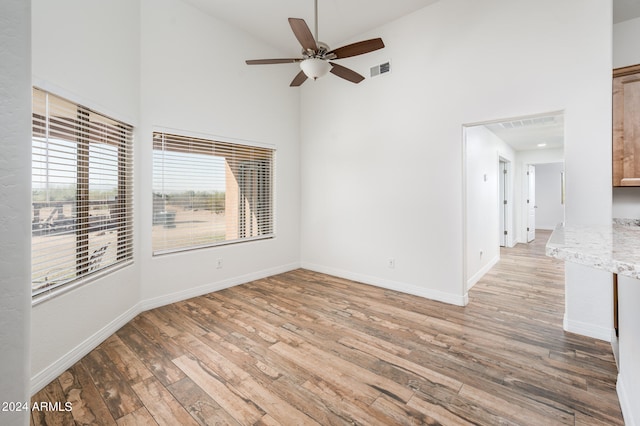 empty room featuring a high ceiling, light hardwood / wood-style floors, and ceiling fan