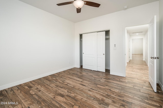 unfurnished bedroom with a closet, wood-type flooring, and ceiling fan