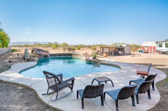 view of pool with a patio, an outbuilding, and pool water feature