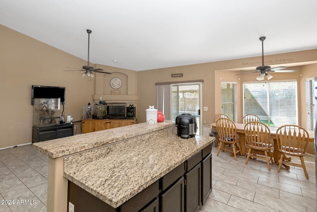 kitchen featuring dark brown cabinets, light stone counters, and a center island