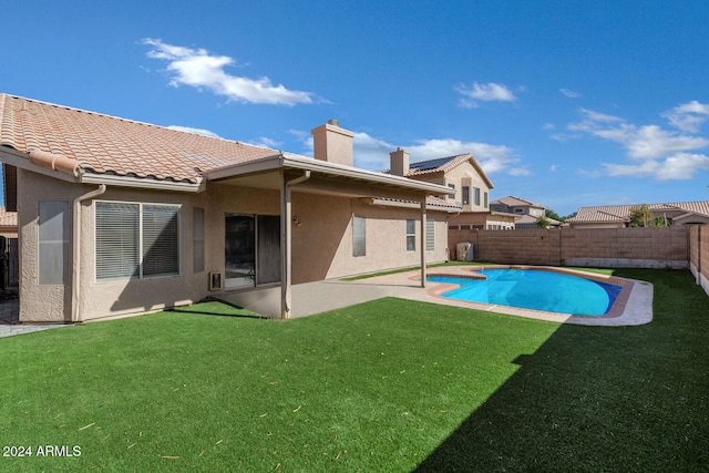 rear view of house featuring a fenced in pool, a patio, and a yard