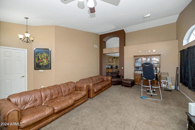 carpeted living room with a high ceiling and ceiling fan with notable chandelier