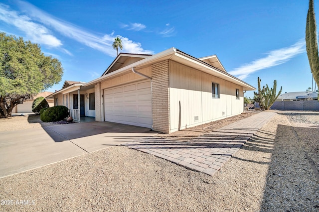 view of property exterior with driveway, brick siding, crawl space, and an attached garage