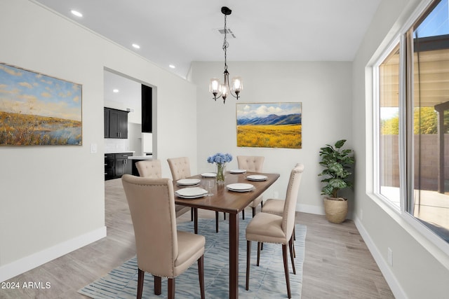 dining space featuring vaulted ceiling, a healthy amount of sunlight, a notable chandelier, and light wood-type flooring