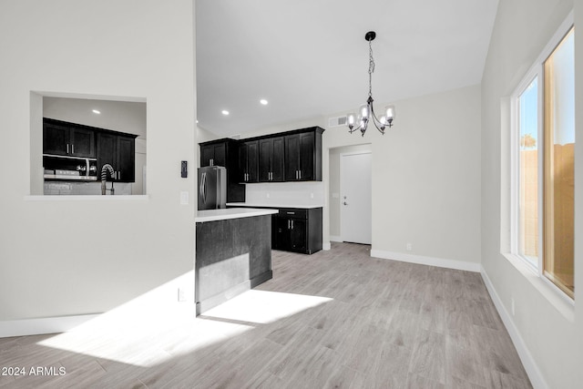 kitchen featuring a chandelier, pendant lighting, stainless steel appliances, and light hardwood / wood-style floors