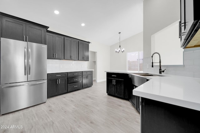 kitchen featuring decorative backsplash, light wood-type flooring, decorative light fixtures, stainless steel refrigerator, and lofted ceiling