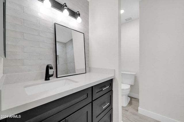 bathroom with toilet, vanity, and hardwood / wood-style flooring