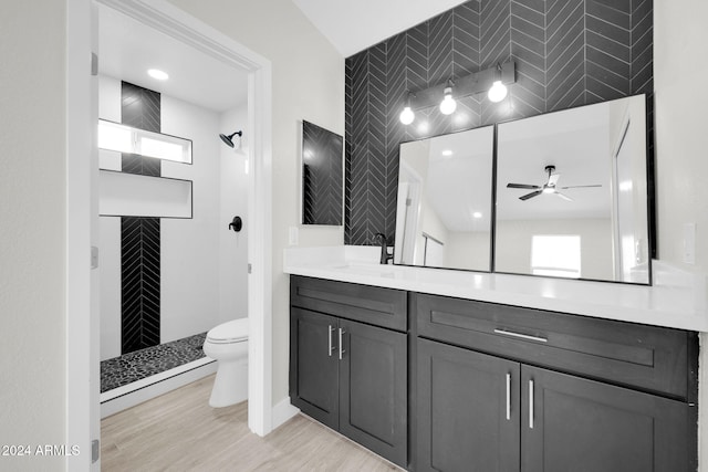 bathroom with a shower, hardwood / wood-style flooring, ceiling fan, toilet, and tile walls