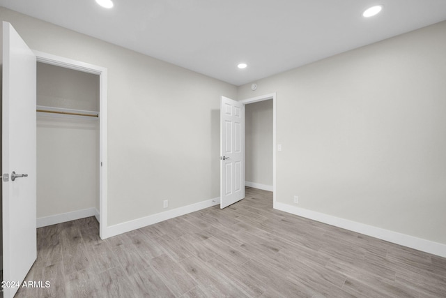 unfurnished bedroom with light wood-type flooring and a closet