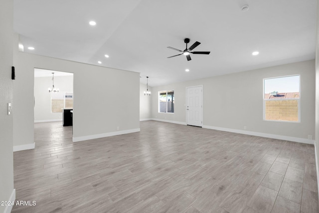 unfurnished living room featuring ceiling fan with notable chandelier and light hardwood / wood-style flooring