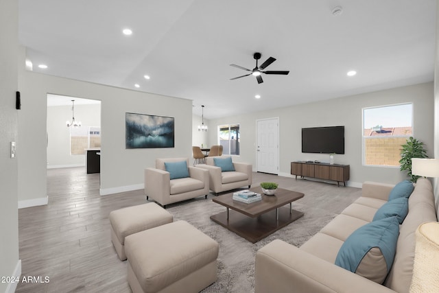 living room featuring a wealth of natural light, ceiling fan with notable chandelier, and light wood-type flooring