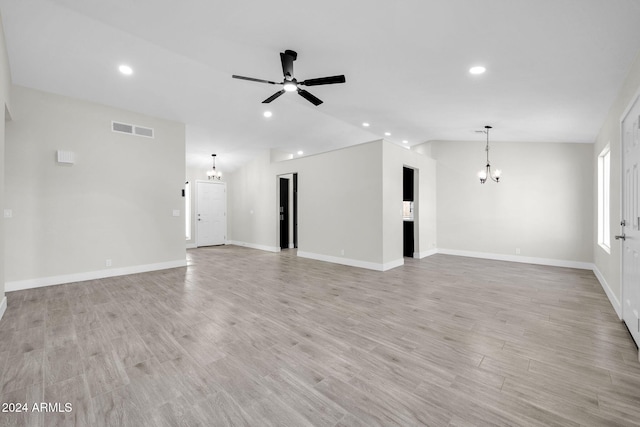 unfurnished living room with ceiling fan with notable chandelier, lofted ceiling, and light hardwood / wood-style flooring