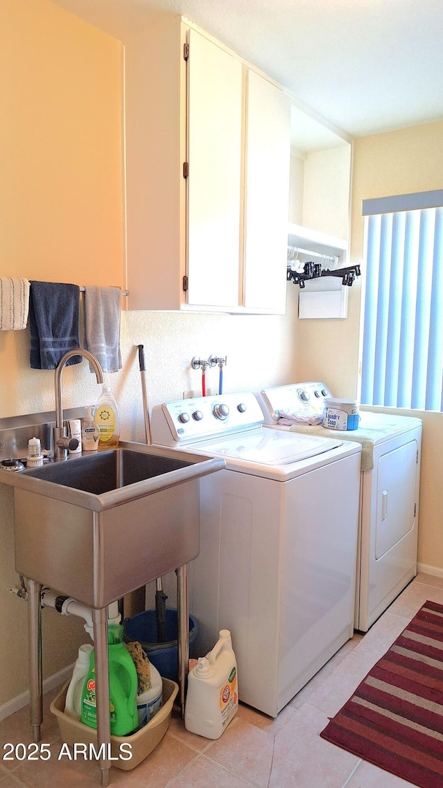 washroom with a sink, light tile patterned flooring, washing machine and dryer, and cabinet space