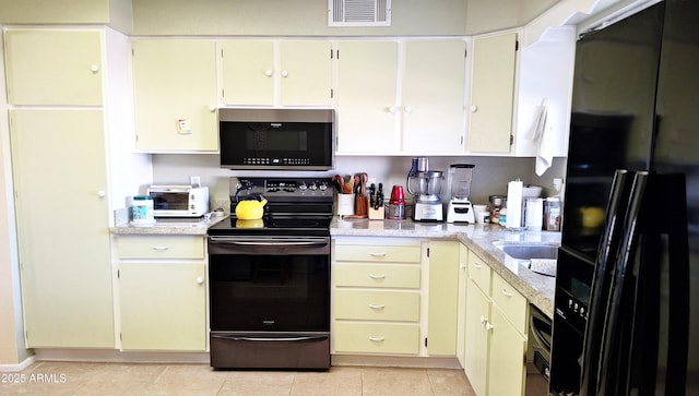 kitchen featuring a toaster, light tile patterned floors, light countertops, visible vents, and black appliances