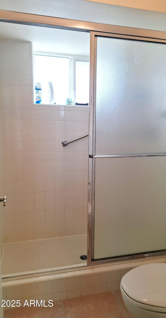 full bath featuring a shower stall, toilet, and tile patterned floors