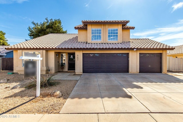 view of front of house featuring driveway, a tiled roof, fence, and stucco siding