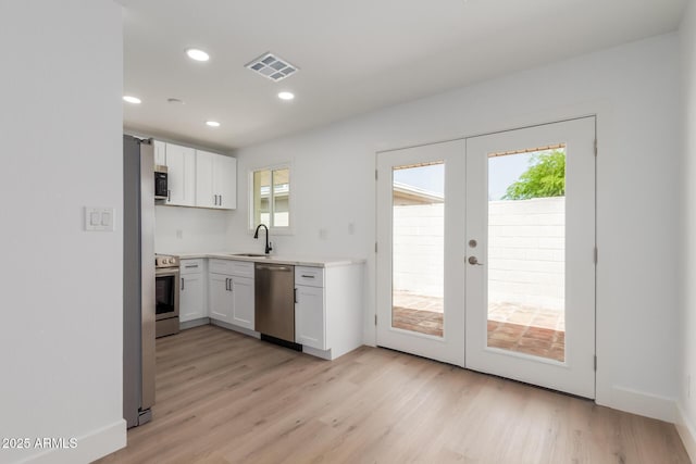kitchen featuring visible vents, white cabinets, french doors, a sink, and appliances with stainless steel finishes
