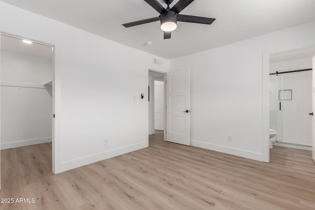 unfurnished bedroom featuring a closet, visible vents, baseboards, light wood-type flooring, and a spacious closet