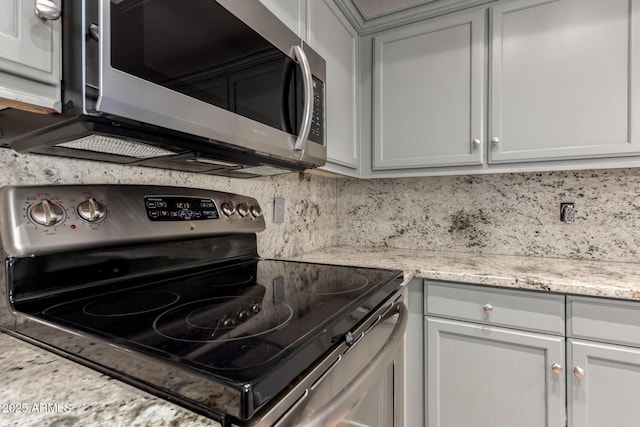 kitchen with light stone counters, appliances with stainless steel finishes, and tasteful backsplash