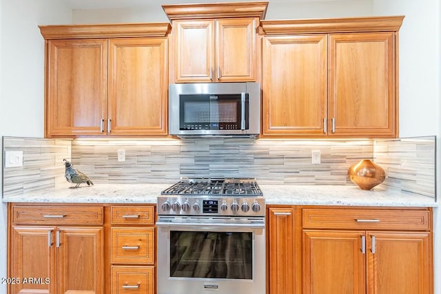 kitchen with light stone counters, stainless steel appliances, and backsplash