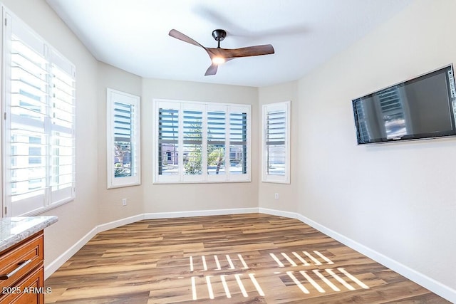 unfurnished room featuring hardwood / wood-style floors, a healthy amount of sunlight, and ceiling fan