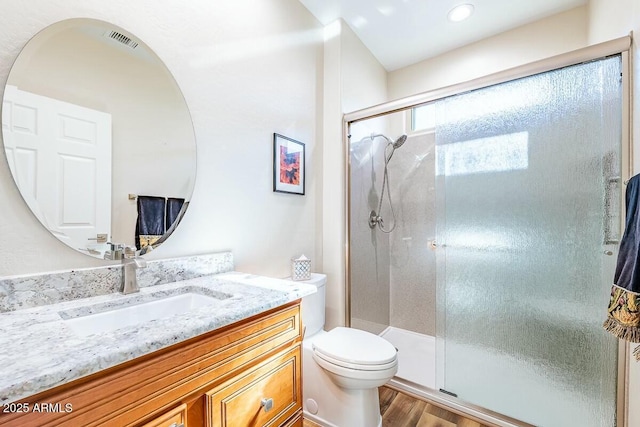 bathroom featuring vanity, hardwood / wood-style flooring, a shower with door, and toilet