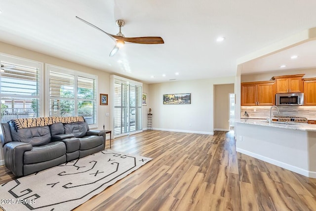 living room with sink, light hardwood / wood-style flooring, and ceiling fan