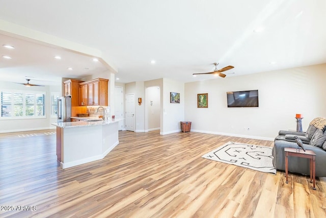 living room with ceiling fan, sink, and light wood-type flooring